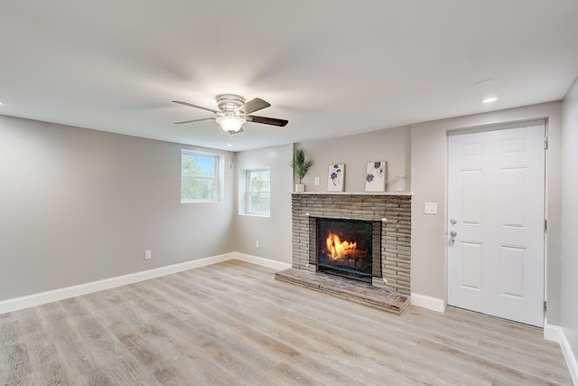 unfurnished living room with light hardwood / wood-style floors, ceiling fan, and a brick fireplace