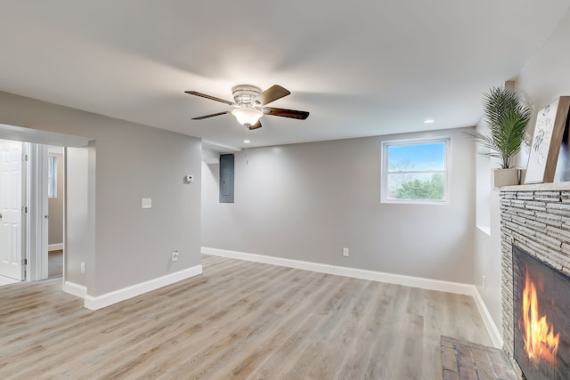 unfurnished living room with a stone fireplace, ceiling fan, light hardwood / wood-style flooring, and electric panel