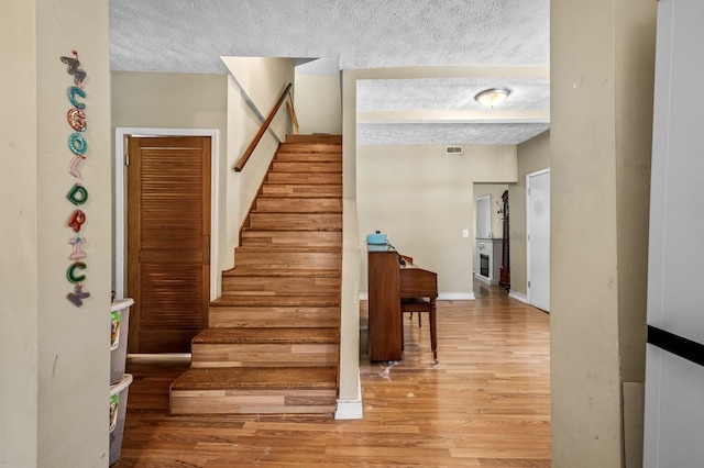 stairway featuring a textured ceiling and hardwood / wood-style flooring