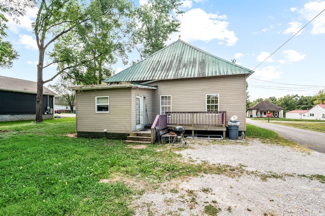 back of property with a deck and a lawn