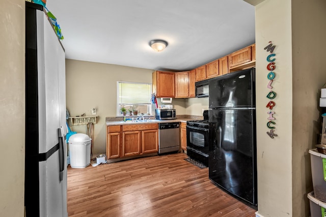 kitchen featuring black appliances, light hardwood / wood-style floors, and sink