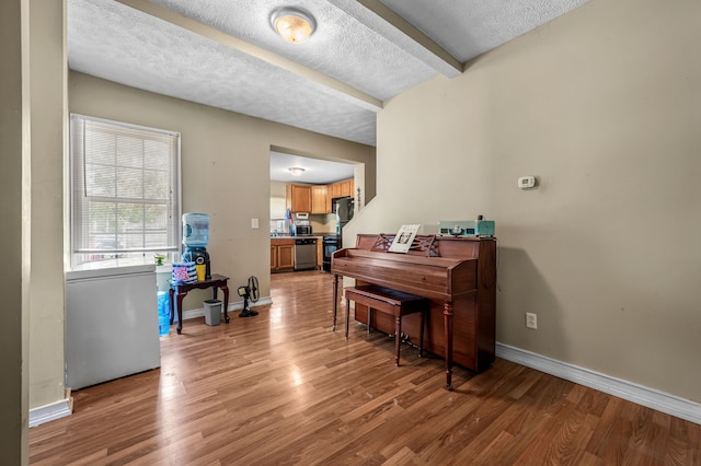 miscellaneous room with beam ceiling, a textured ceiling, and hardwood / wood-style floors