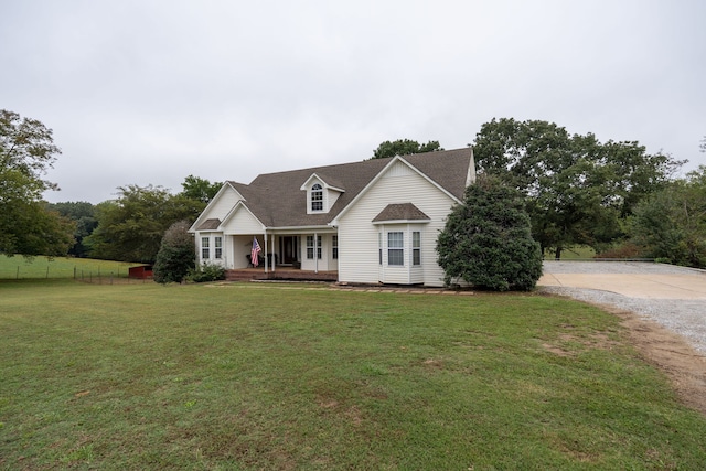 cape cod-style house featuring covered porch and a front yard