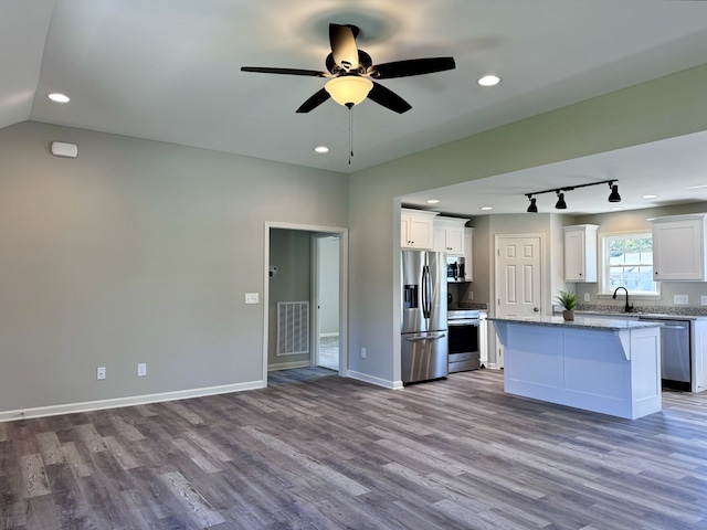 kitchen featuring appliances with stainless steel finishes, light hardwood / wood-style floors, light stone counters, white cabinets, and a kitchen island