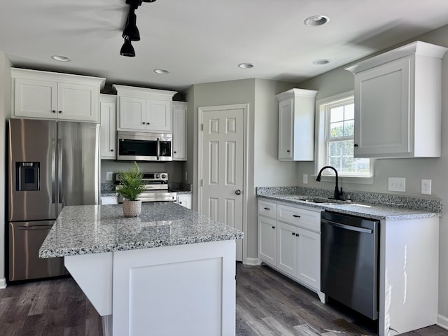 kitchen with dark wood-type flooring, sink, white cabinetry, a kitchen island, and appliances with stainless steel finishes