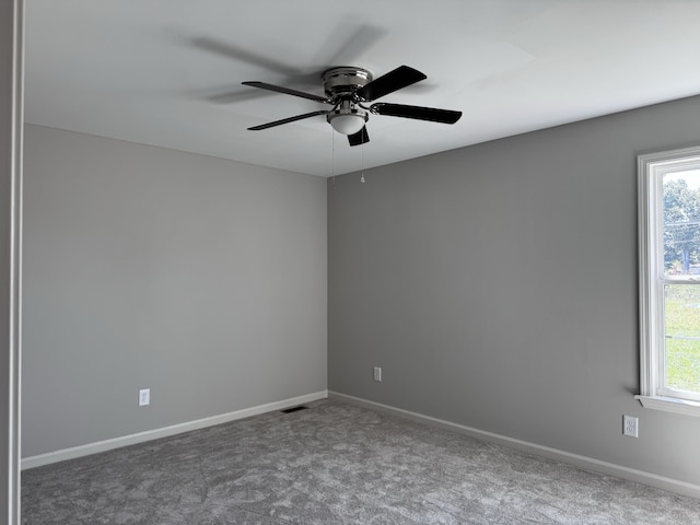 carpeted spare room with ceiling fan and plenty of natural light