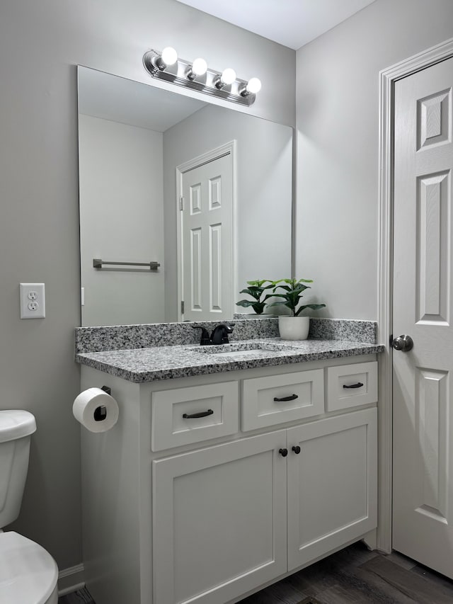 bathroom featuring vanity, toilet, and hardwood / wood-style flooring