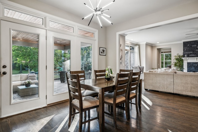 dining area with ceiling fan with notable chandelier, crown molding, dark hardwood / wood-style flooring, and a large fireplace