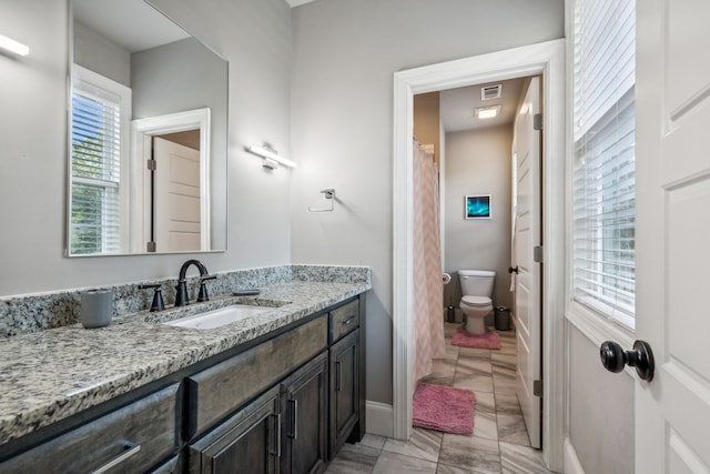 bathroom with plenty of natural light, vanity, and toilet