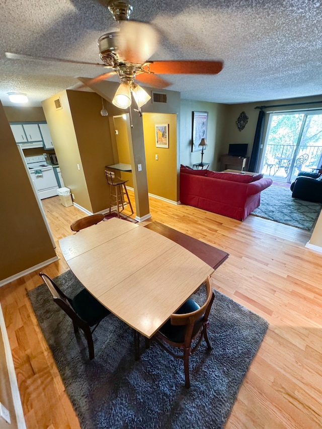 dining room featuring a textured ceiling, wood-type flooring, vaulted ceiling, and ceiling fan