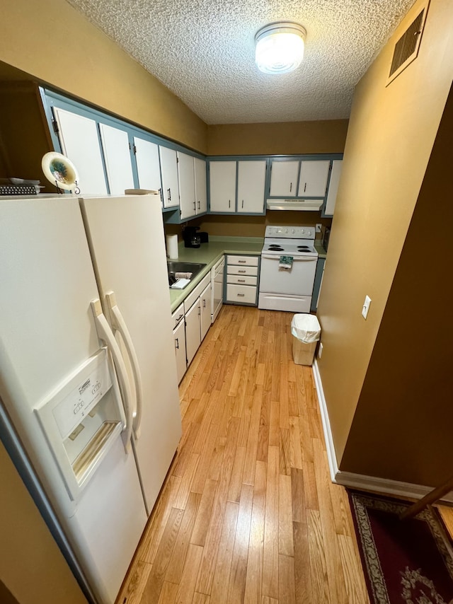 kitchen featuring light wood-type flooring, a textured ceiling, sink, white cabinets, and white appliances