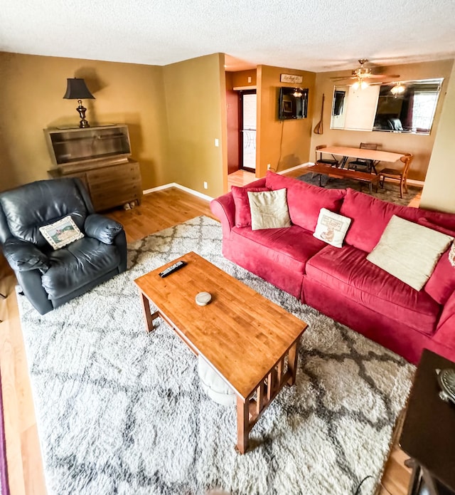 living room featuring wood-type flooring, a textured ceiling, and ceiling fan