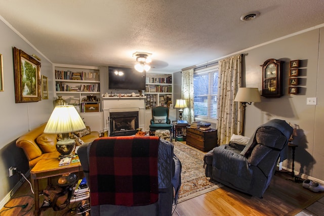 living room featuring ornamental molding, light wood-type flooring, a textured ceiling, and ceiling fan