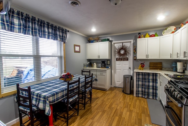 kitchen featuring crown molding, black gas range oven, light hardwood / wood-style flooring, and white cabinets