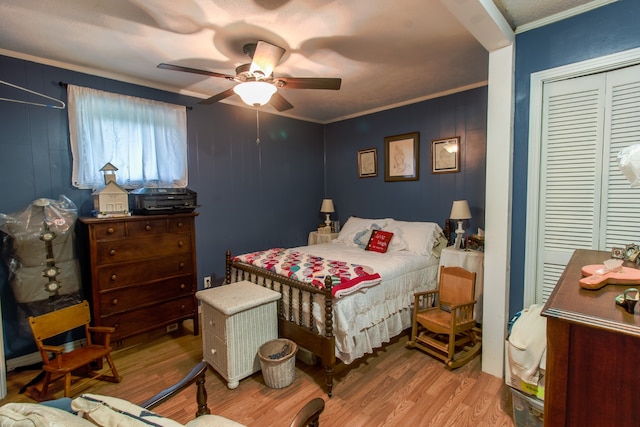 bedroom featuring light hardwood / wood-style floors, ornamental molding, ceiling fan, and a closet