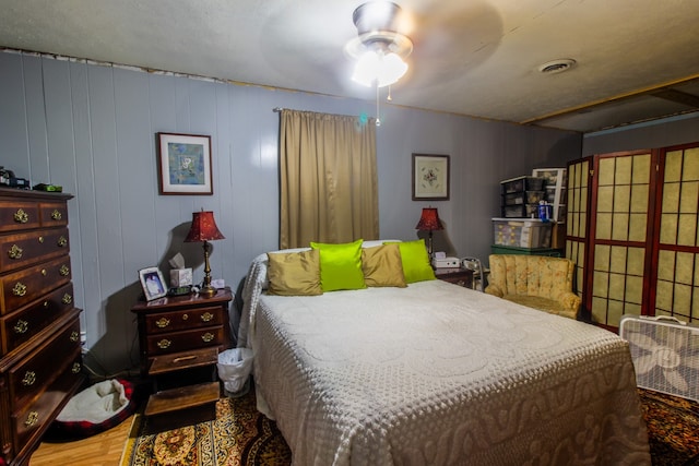 bedroom featuring wood walls, ceiling fan, and hardwood / wood-style floors