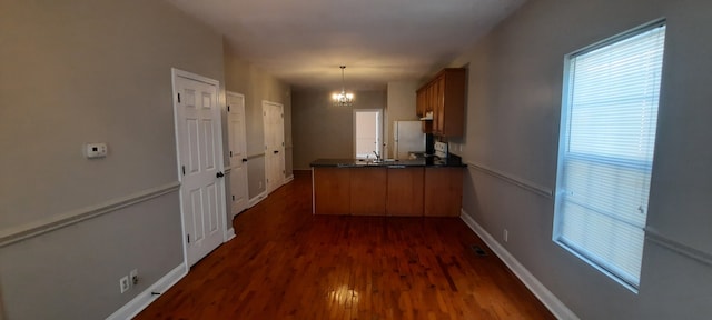 hallway with dark hardwood / wood-style floors and a notable chandelier