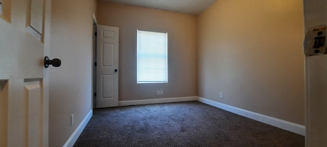 unfurnished room featuring dark colored carpet