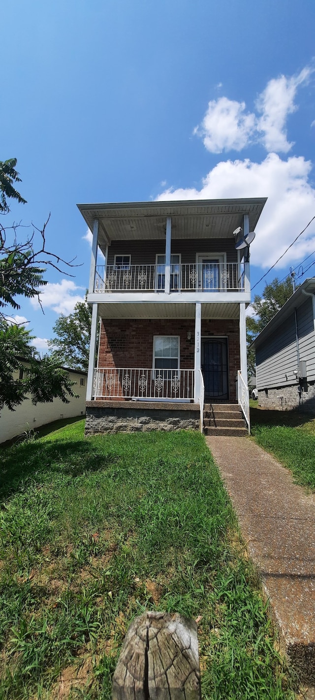 view of front of home with a front yard and a balcony