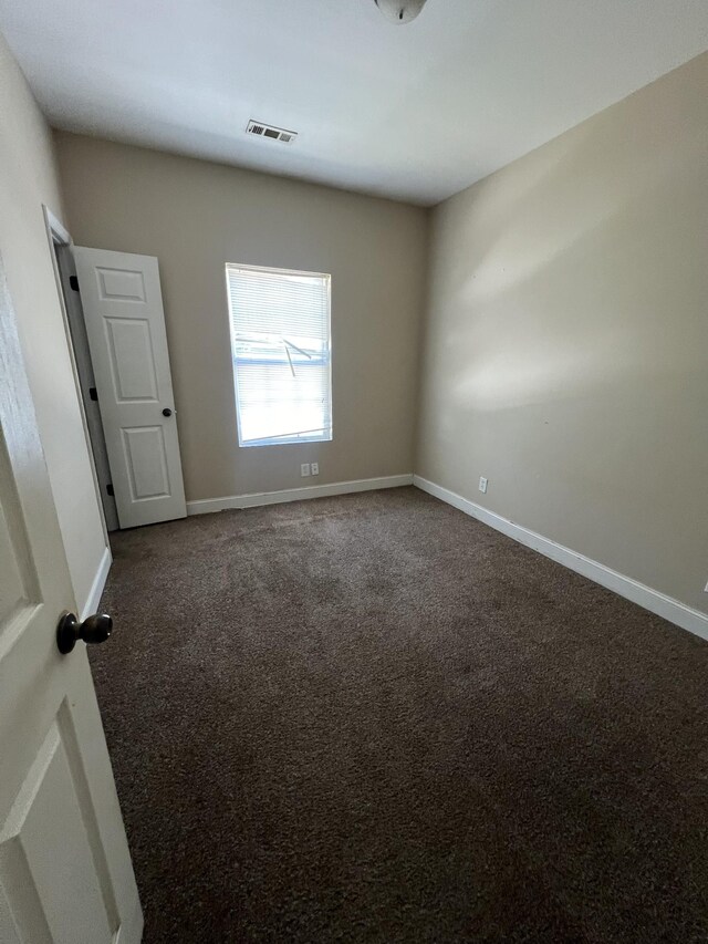 spare room with dark carpet