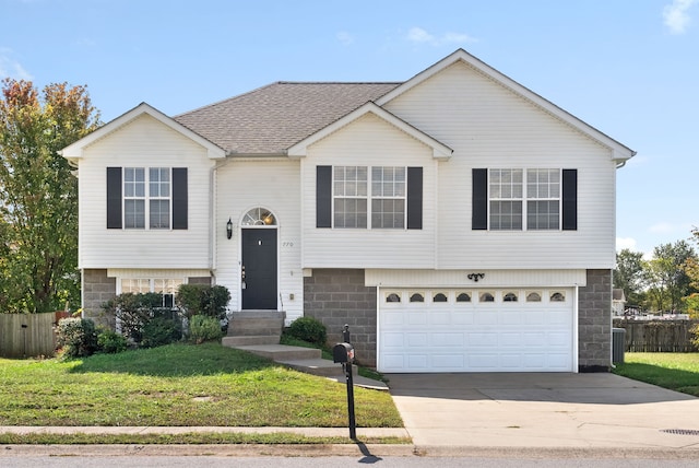 raised ranch featuring a front lawn and a garage