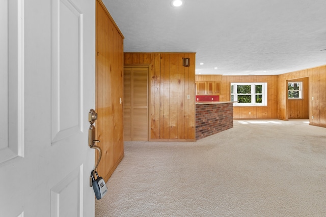 carpeted living room with a textured ceiling and wood walls