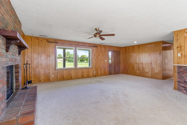 unfurnished living room with a fireplace, wood walls, and carpet flooring