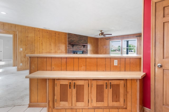 bar featuring a brick fireplace, wooden walls, ceiling fan, and light tile patterned flooring