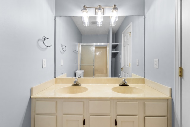 bathroom with vanity, a shower with shower door, and toilet