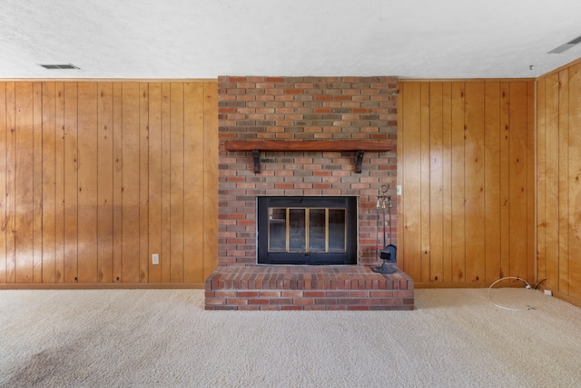 unfurnished living room with carpet floors, a textured ceiling, wooden walls, and a fireplace