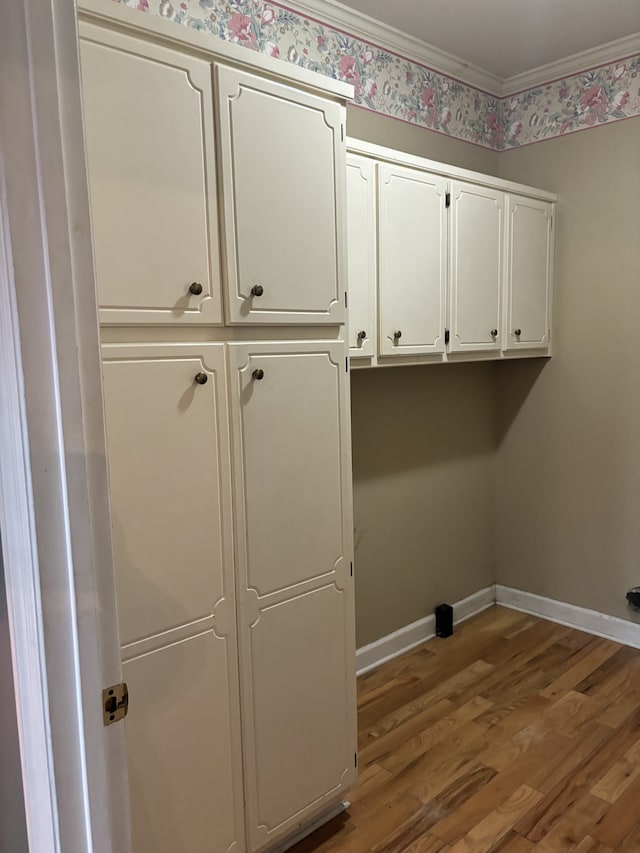 clothes washing area with hardwood / wood-style floors and crown molding