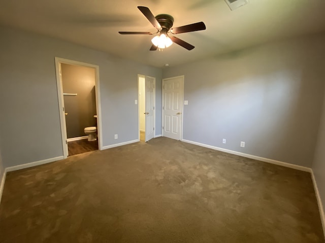 unfurnished bedroom featuring ceiling fan, ensuite bath, and dark colored carpet