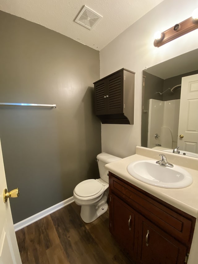 bathroom featuring vanity, walk in shower, a textured ceiling, hardwood / wood-style flooring, and toilet