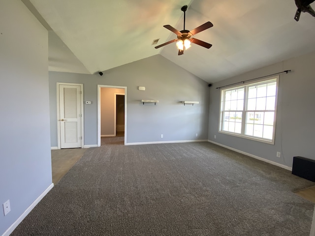 unfurnished living room with ceiling fan, vaulted ceiling, and dark carpet