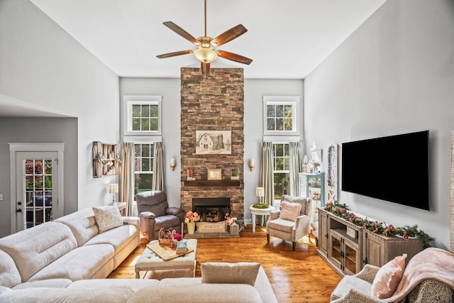 living room with ceiling fan, a fireplace, light hardwood / wood-style floors, and a healthy amount of sunlight