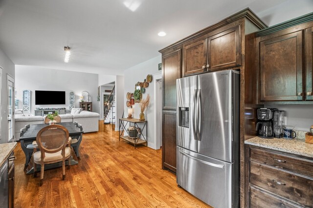 kitchen featuring dark brown cabinetry, stainless steel refrigerator with ice dispenser, light stone counters, and light hardwood / wood-style floors