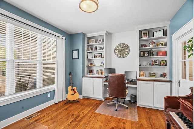 home office featuring built in desk and dark hardwood / wood-style flooring