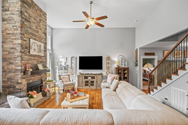 living room featuring a high ceiling, a fireplace, light hardwood / wood-style flooring, and plenty of natural light