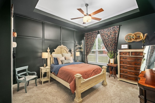 bedroom featuring ceiling fan, light colored carpet, a tray ceiling, and ornamental molding