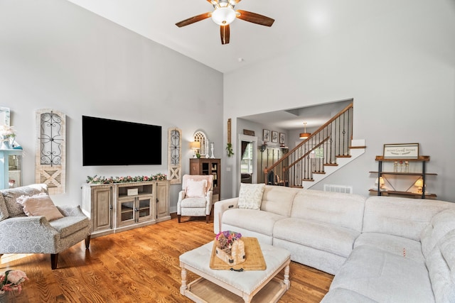 living room with wood-type flooring, a high ceiling, and ceiling fan