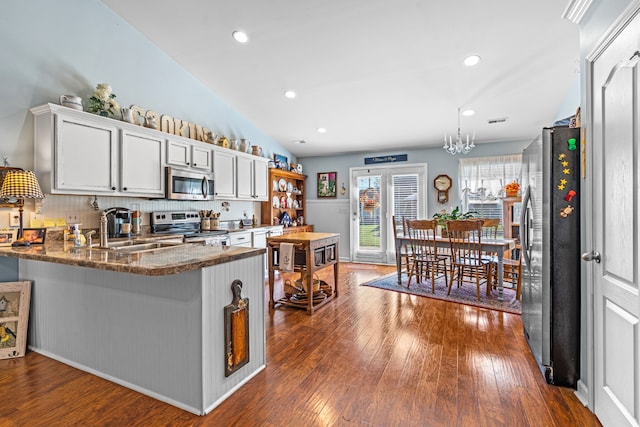 kitchen with lofted ceiling, stainless steel appliances, dark hardwood / wood-style flooring, kitchen peninsula, and white cabinetry