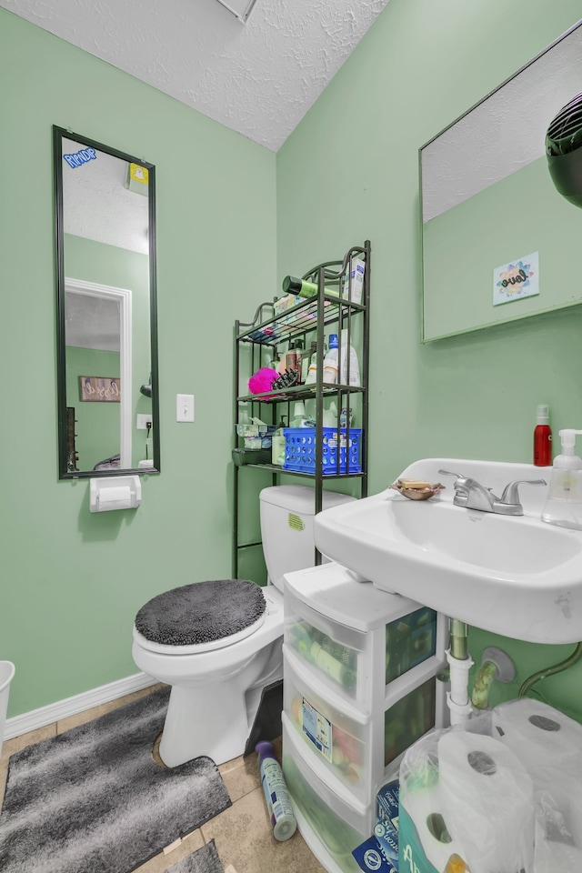 bathroom with a textured ceiling, sink, and toilet