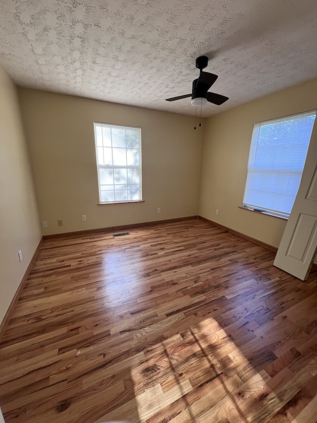 unfurnished room featuring ceiling fan, a textured ceiling, and light wood-type flooring