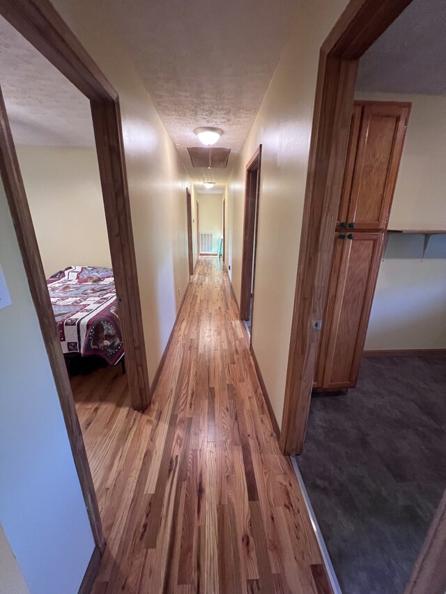 hall with a textured ceiling and hardwood / wood-style floors