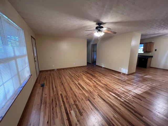 unfurnished living room featuring wood-type flooring, a textured ceiling, and ceiling fan