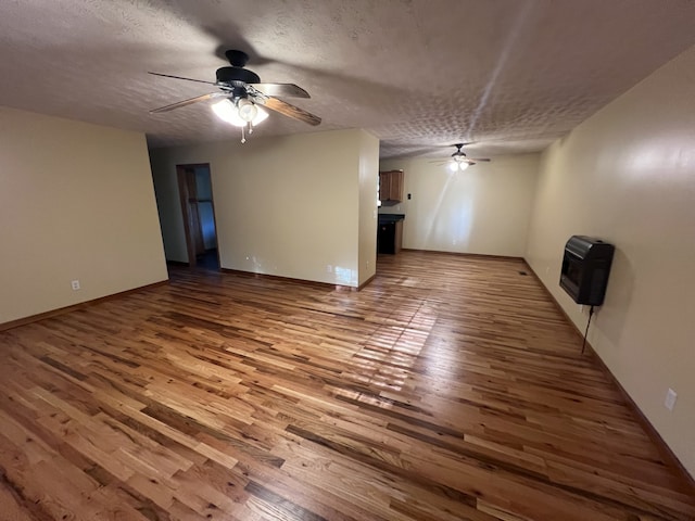 unfurnished living room with heating unit, ceiling fan, a textured ceiling, and hardwood / wood-style floors