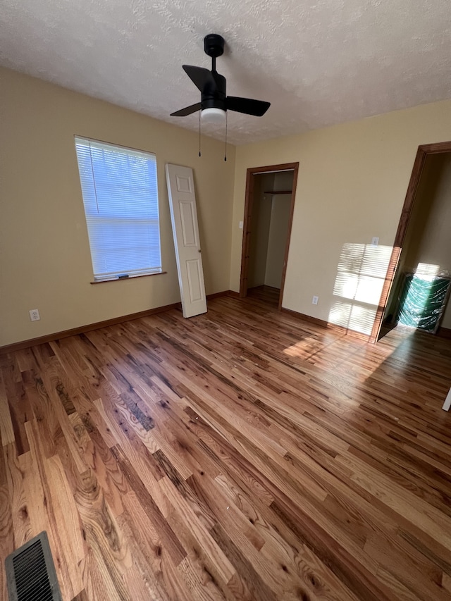 unfurnished bedroom with light hardwood / wood-style flooring, ceiling fan, and a textured ceiling