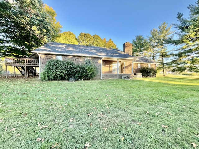 rear view of property featuring a wooden deck and a yard