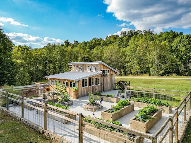 144 Abberly Ln, Hohenwald, TN 38462 - rear view of property featuring a garden, metal roof, a view of trees, a patio area, and an outdoor structure