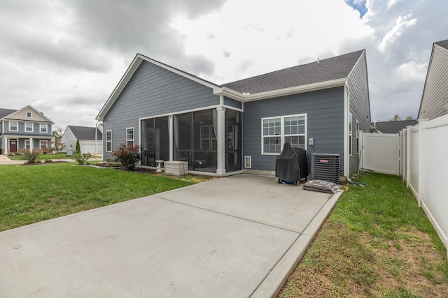 rear view of property featuring cooling unit, a sunroom, and a yard